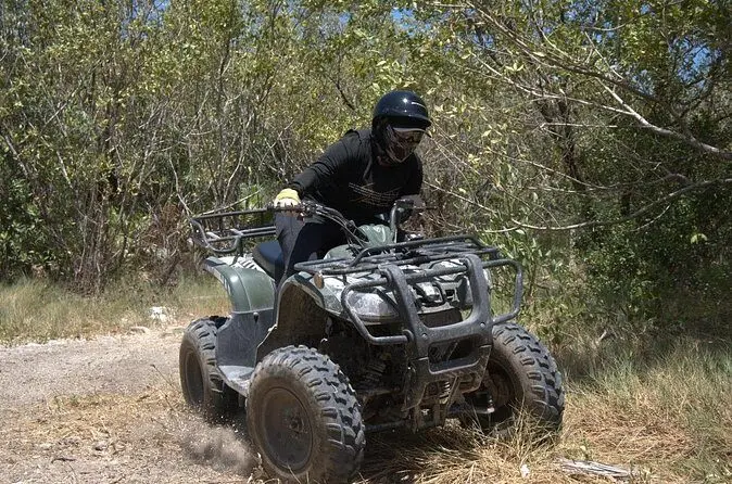 ATV rider rounding a sandy jungle trail